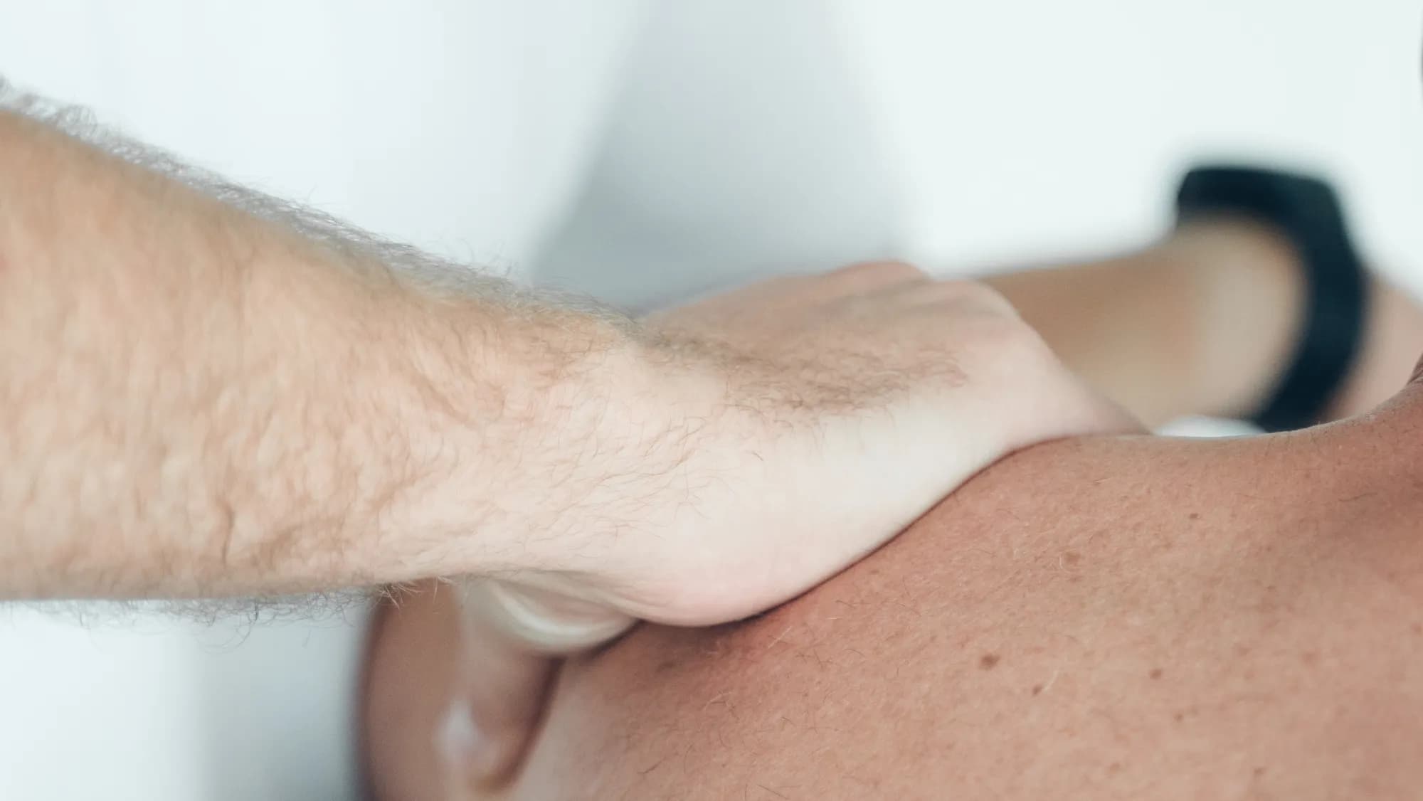 Joachim Schweitzer behandelt die Schulter eines Patienten in der Praxis in Passau