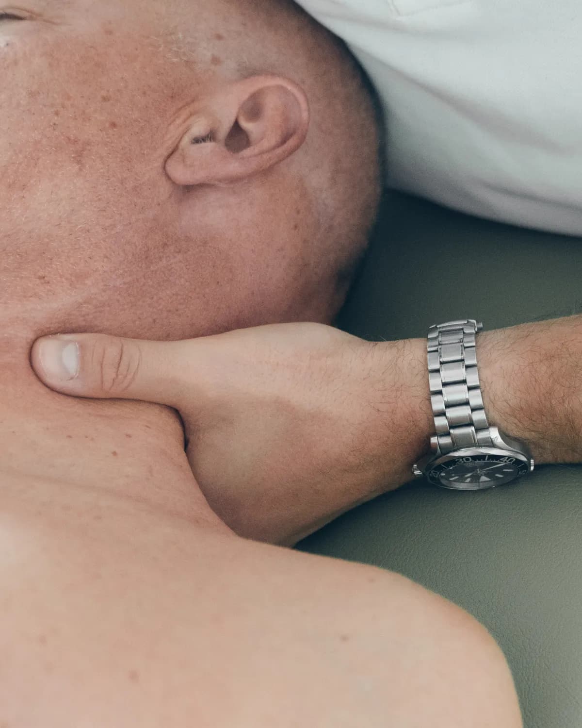 Therapeutenhand behandelt die Muskulatur an Nacken und Kieferwinkel