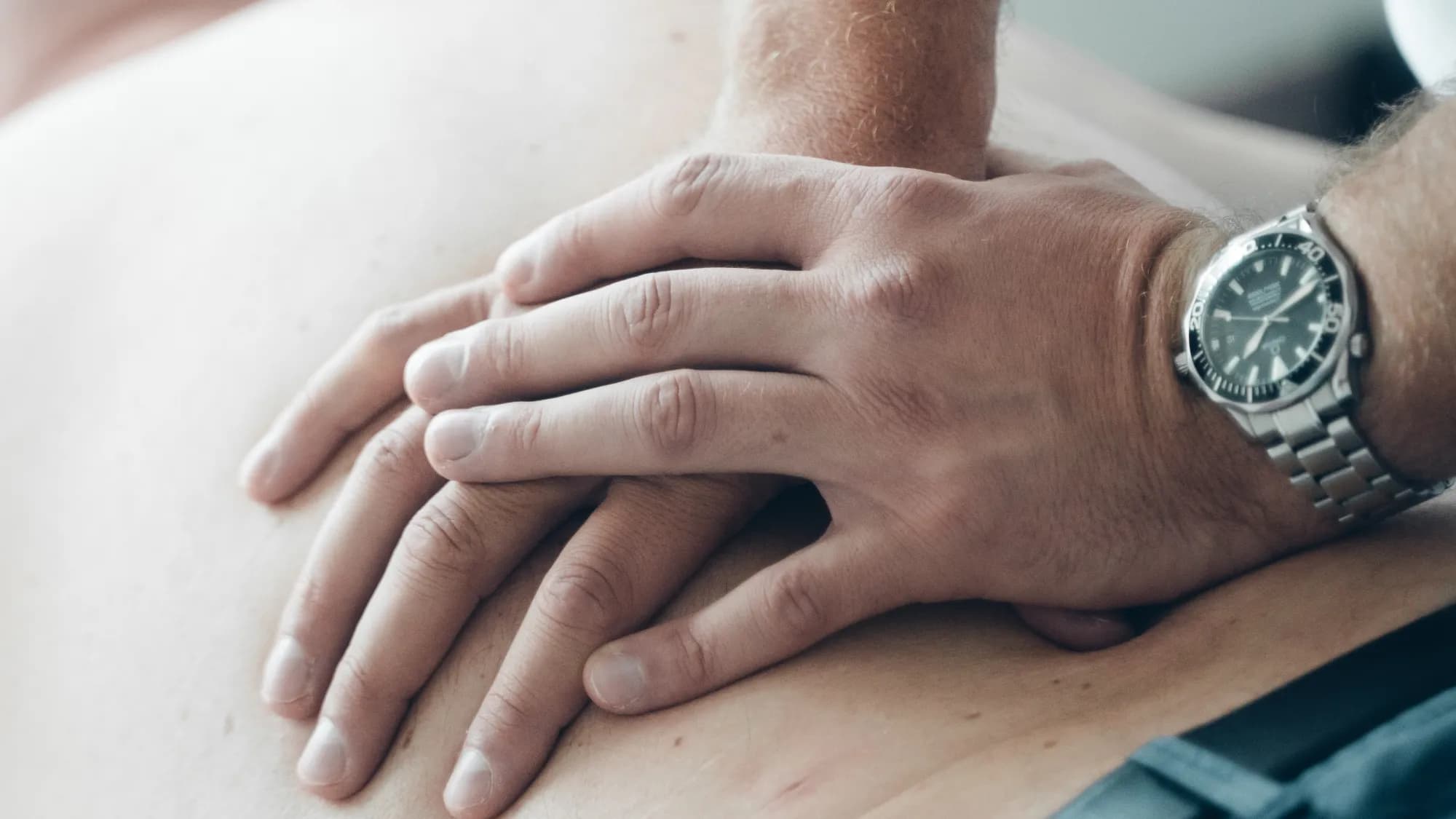 Flach aufgelegte Therapeutenhände am Rücken, sanfte Behandlung in der Praxis Schweitzer in Passau