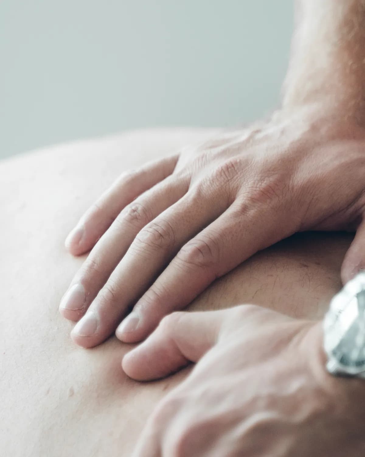 Therapeutenhände setzen gezielt an einer Stelle am Rücken an